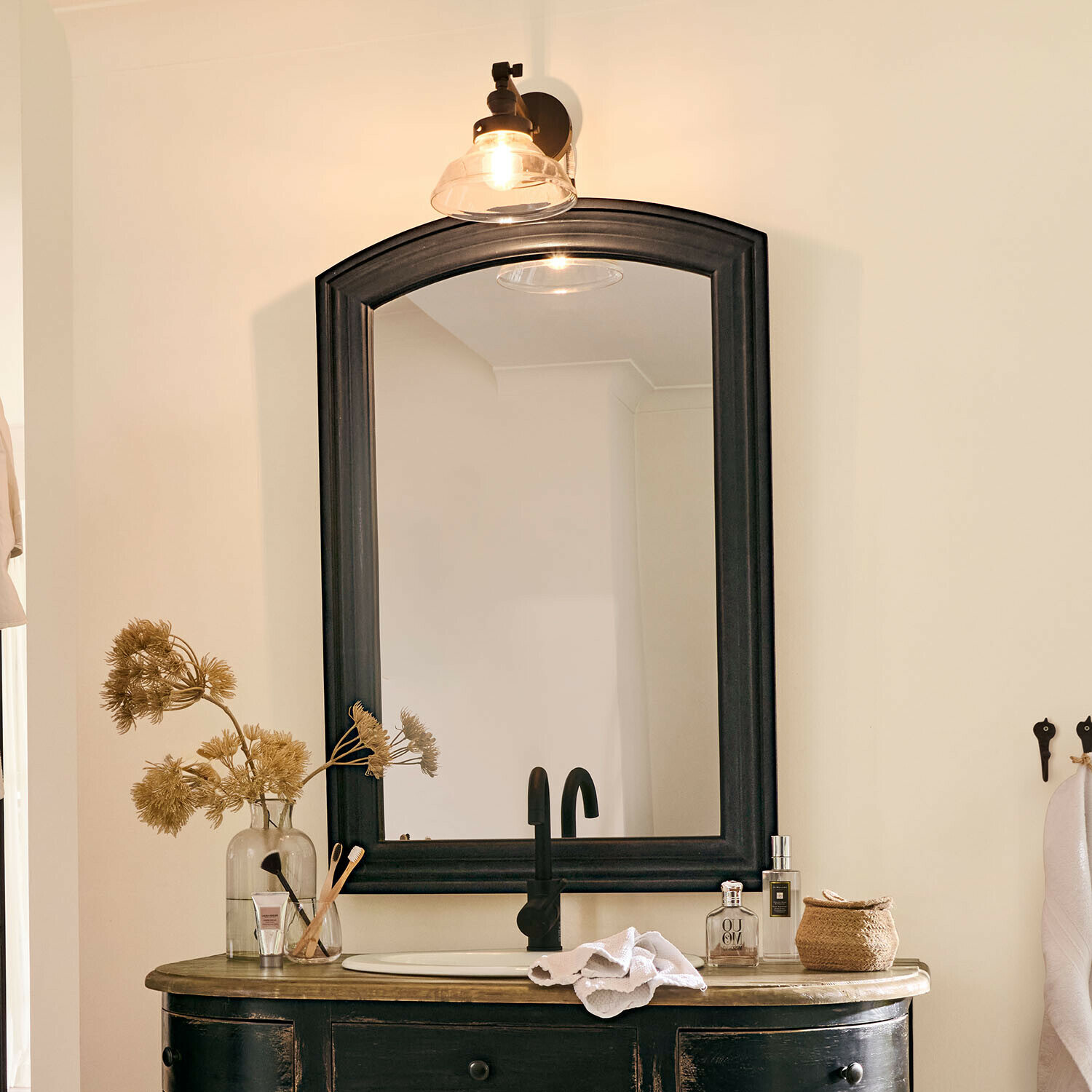 Schwarzer Holzrahmen-Spiegel über Waschbecken mit schwarzem Wasserhahn und Badezimmerdekoration