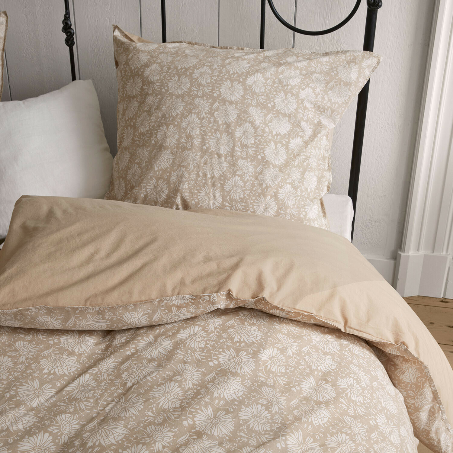 Bettwäsche Jouvenay Beige Baumwoll-Bettwäsche mit weißem Blumenmuster auf einem Bett mit Metallrahmen