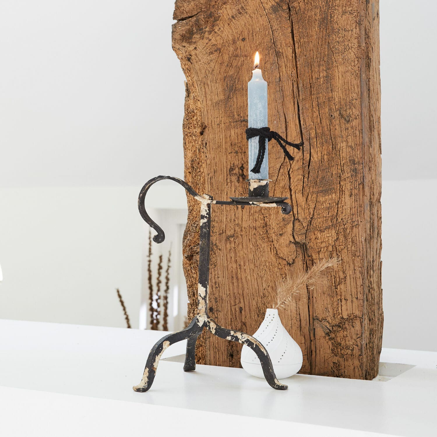 Kerzenhalter Minorville Metall-Kerzenhalter mit abgenutztem schwarzem Lack und blauer Kerze vor weißem und Holz-Hintergrund