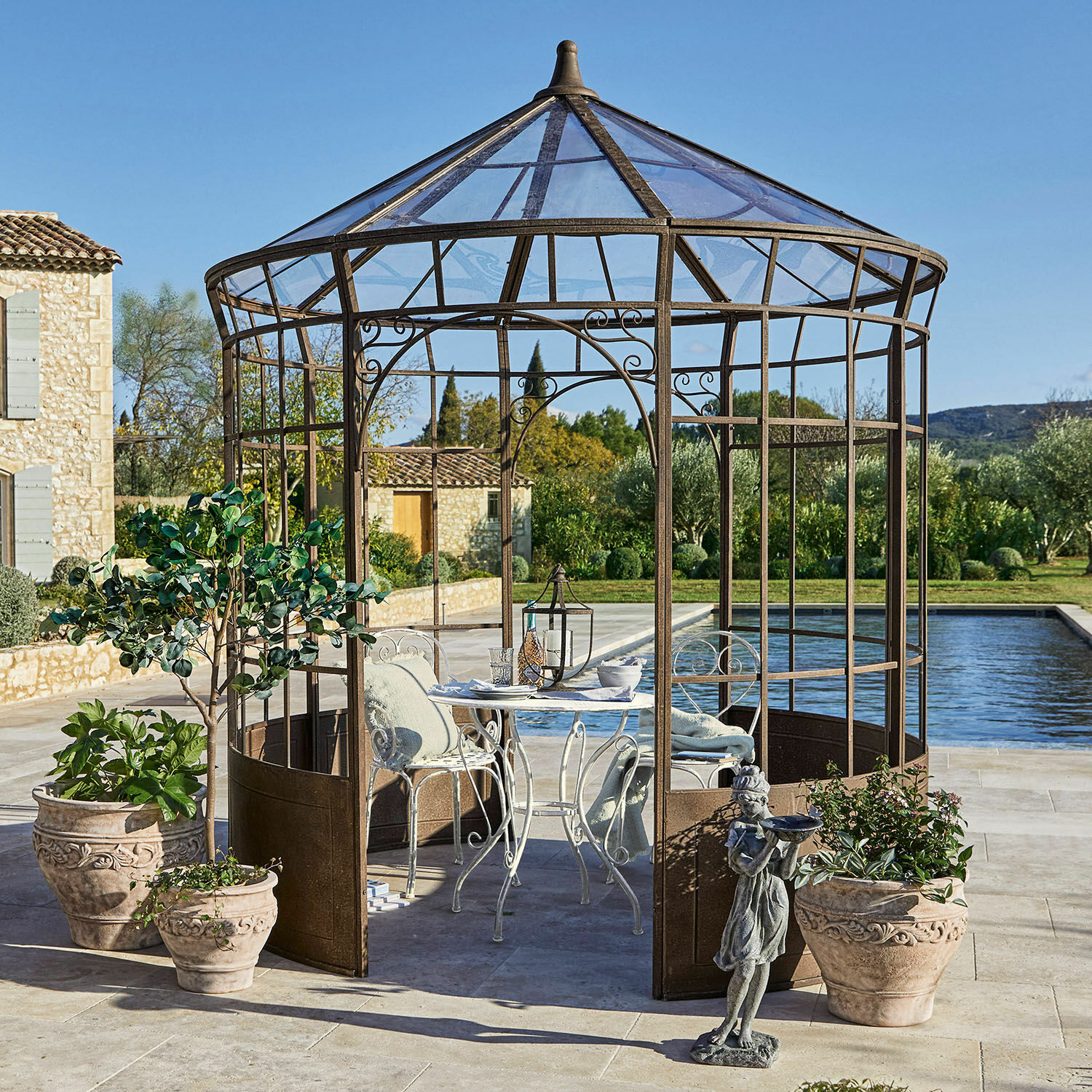 Pavillon Murillo Dekorativer Gartenpavillon aus rostfarbenem Metall mit weißem Tisch und Stühlen auf Terrasse am Pool