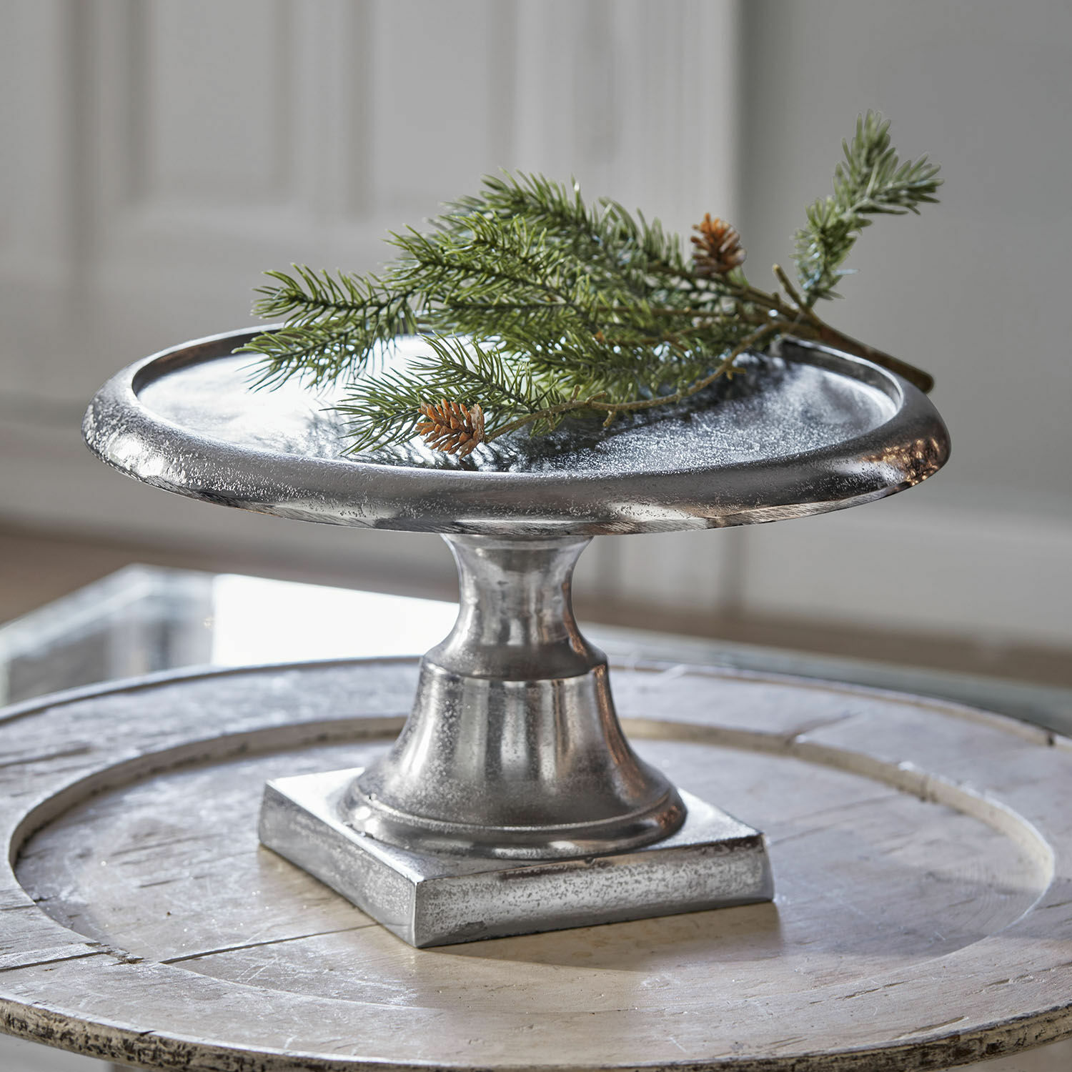 Silberner Metallteller auf Fuß, dekoratives Wohnaccessoire für stilvolle Tischgestaltung