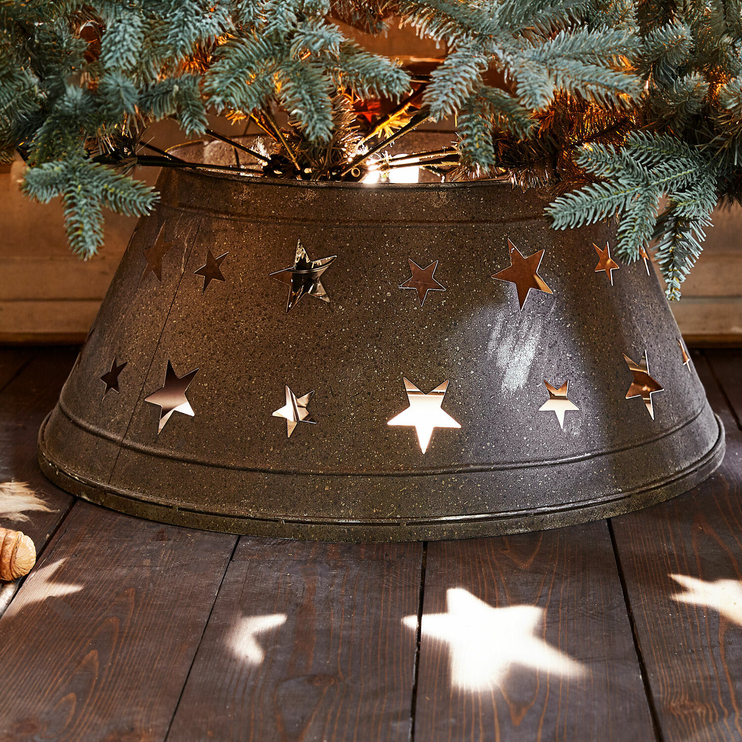 Weihnachtsbaumumrandung Ysabelle Metall-Weihnachtsbaumständer mit sternförmigen Ausschnitten in Dunkelgrau auf Holzboden