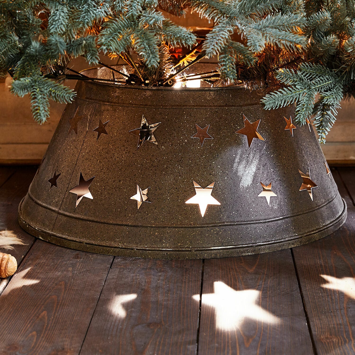 Weihnachtsbaumumrandung Ysabelle Metall-Weihnachtsbaumständer mit sternförmigen Ausschnitten in Dunkelgrau auf Holzboden