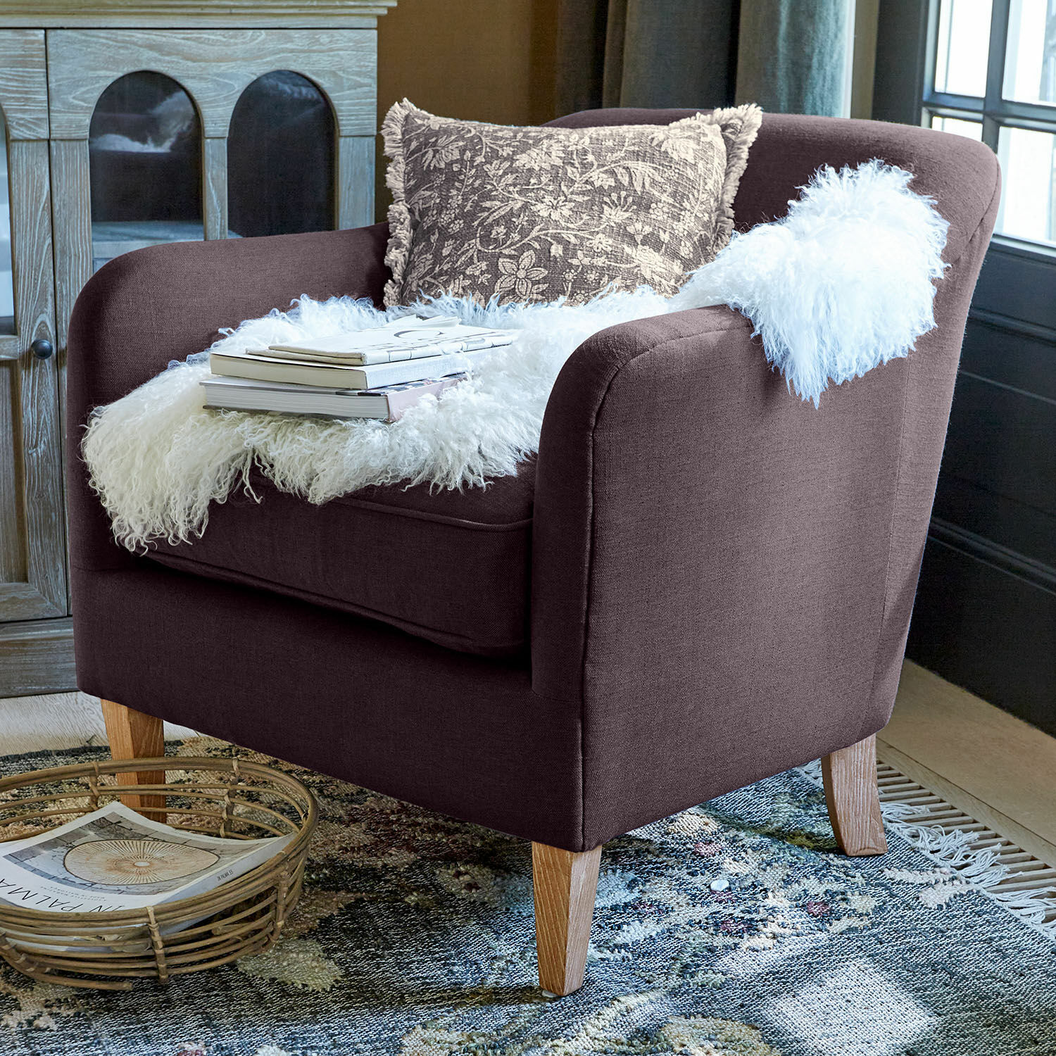 Sessel Jefferson Brauner Polsterfauteuil mit Holzbeinen, dekoriert mit weißem Fellplaid und gemustertem Kissen