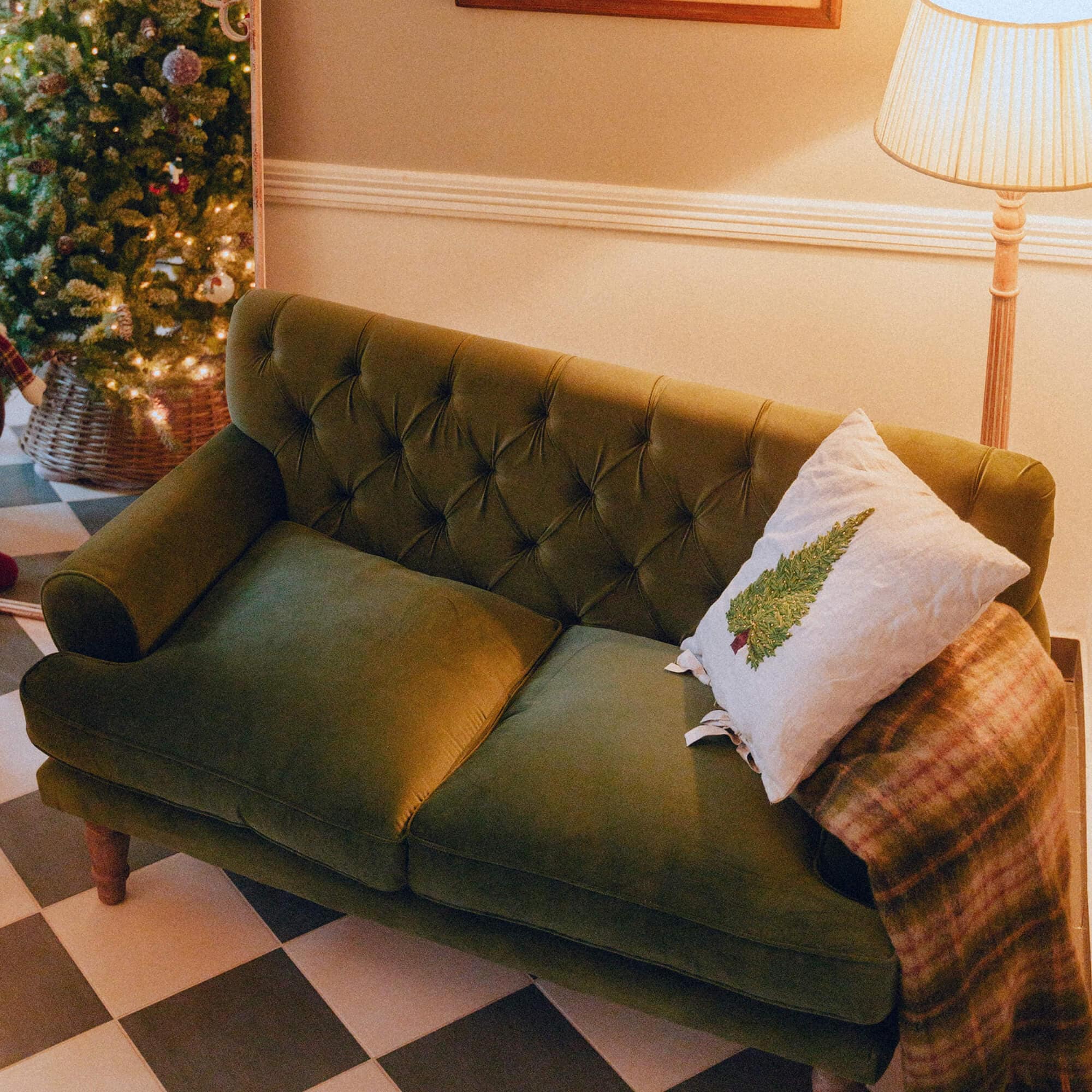 Grünes Samtsofa mit gesteppter Rückenlehne und Weihnachtskissen in gemütlichem Raum