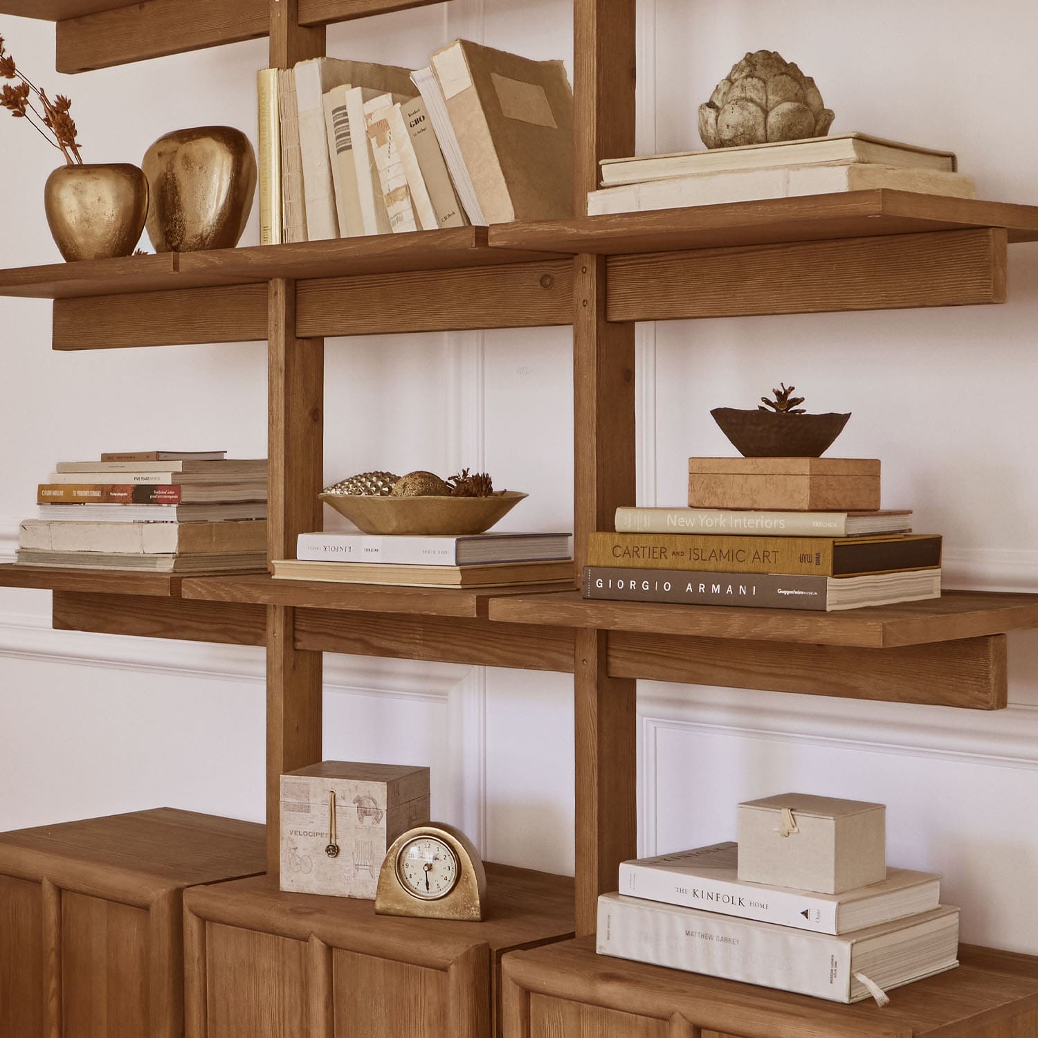 Holzregal mit Büchern, goldenen Dekorationen und Uhr, stilvolle Wohnraumgestaltung