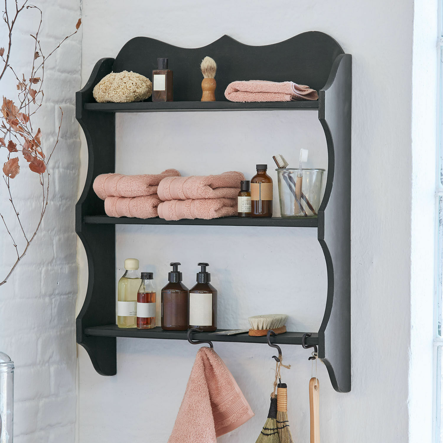Wandregal Ashwick Schwarzes Holzregal mit rosa Handtüchern und Pflegeaccessoires im Badezimmer