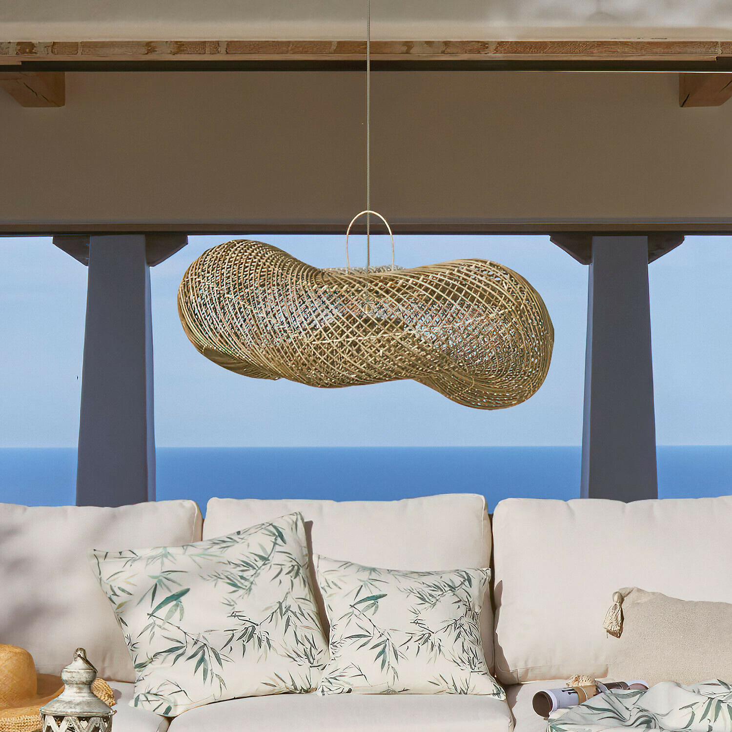 Lampenschirm Amariel Hängelampe aus natürlichem Rattan über weißem Sofa mit Kissen im Blätterdesign, gemütliches Ambiente