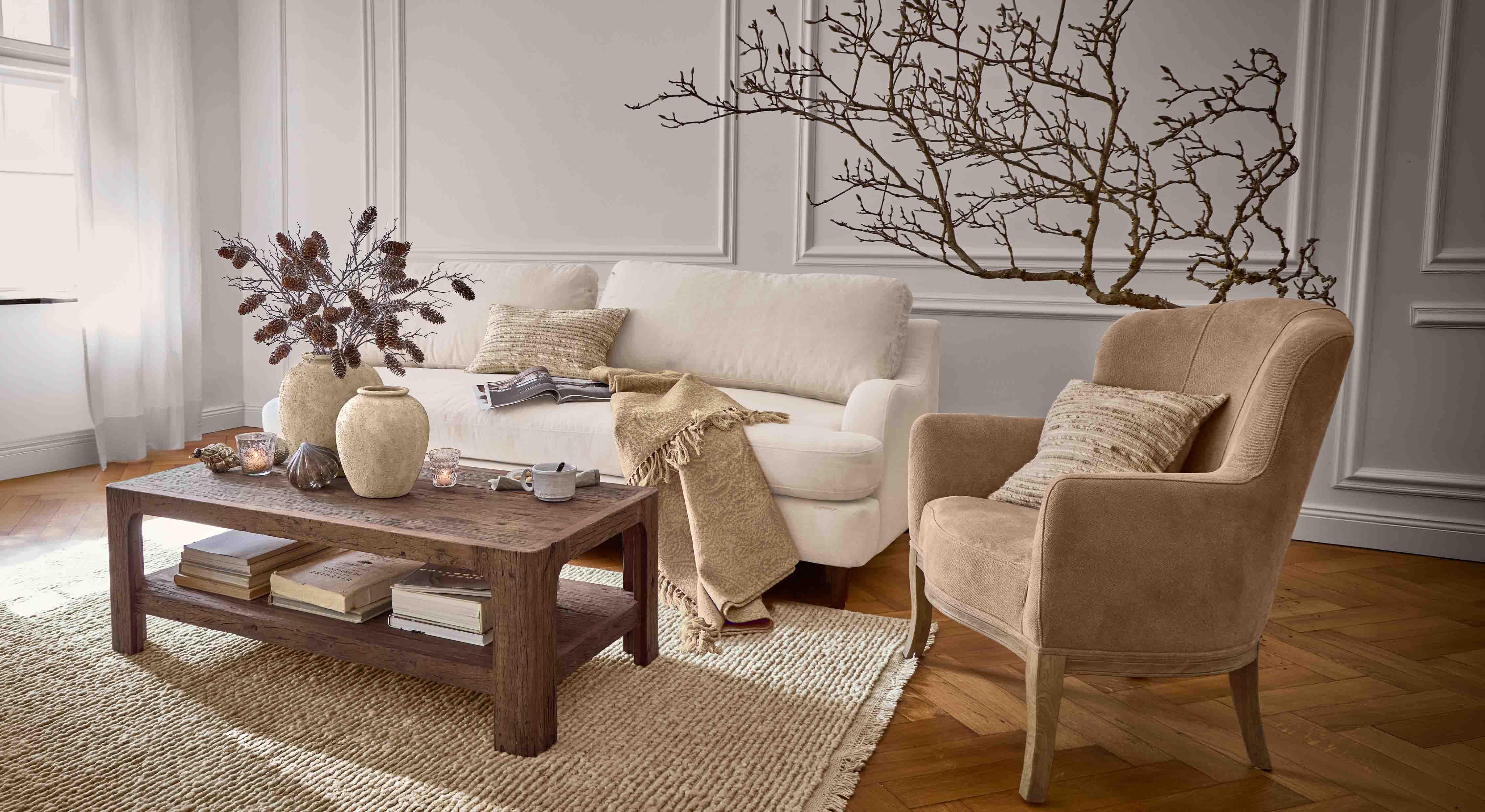 Gemütliches Wohnzimmer mit beigem Sofa, braunem Sessel und rustikalem Holztisch auf Teppich