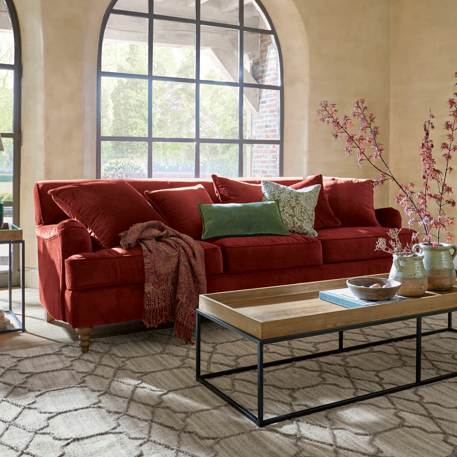 Sofa Isa Rotes Samtsofa mit Kissen und Holzcouchtisch in hellem Wohnzimmer