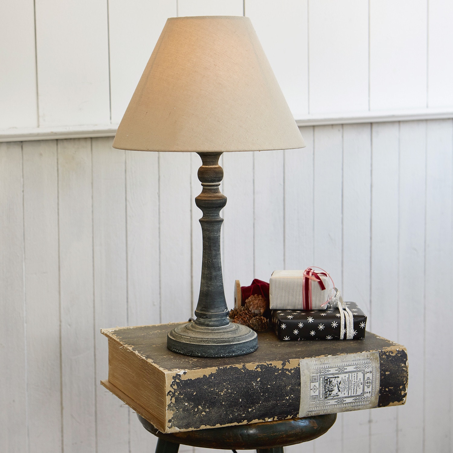 Tischlampe Withby Tischlampe mit beigem Lampenschirm und antik wirkendem schwarzem Fuß vor weißer Wand