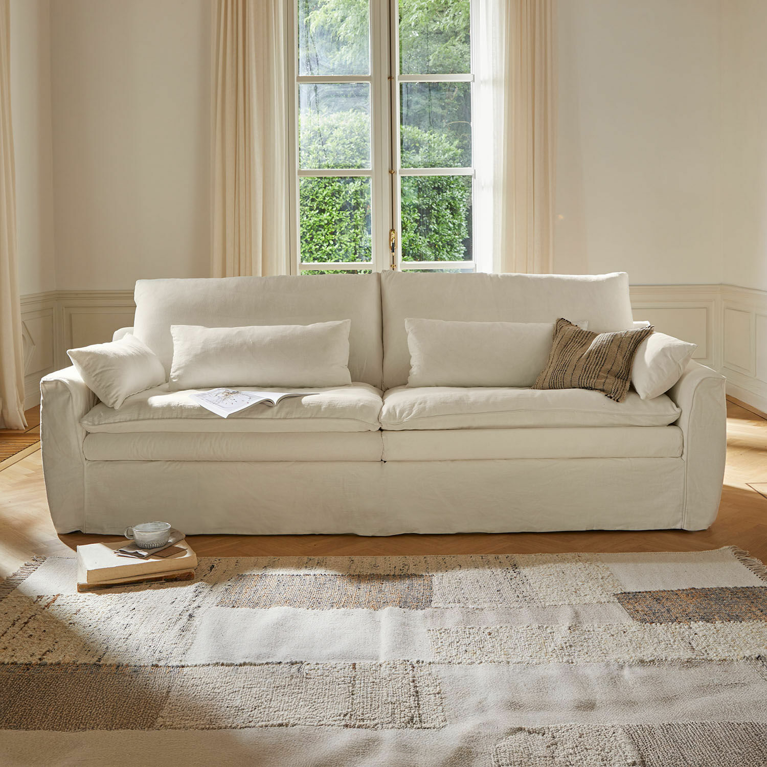 Sofa Dunhaven Beiges Sofa aus Stoff mit Kissen und hellem Teppich in gemütlichem Wohnzimmer