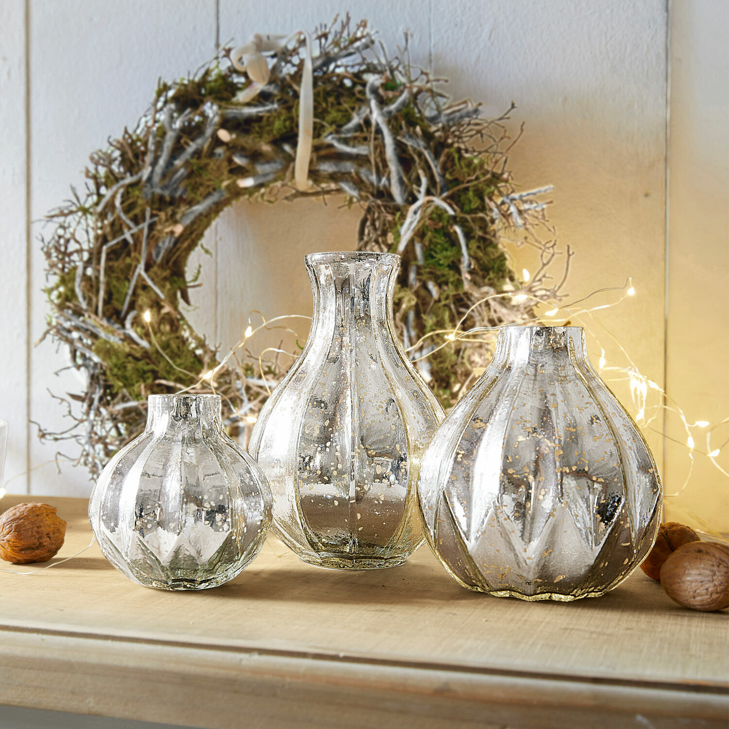 Vase 3er Set Frido Drei dekorative silberne Glasvasen auf Holztisch vor natürlichem Kranz mit Lichterkette
