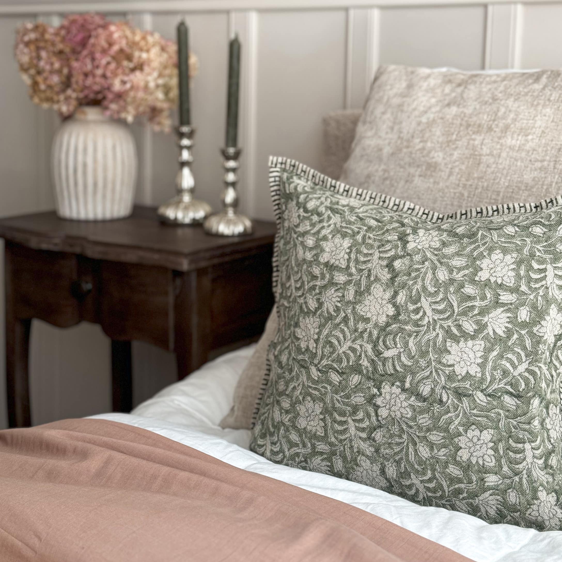 Dekoratives Kissen mit grünem Blumenmuster auf beigem Stoff auf einem Bett im Vintage-Stil