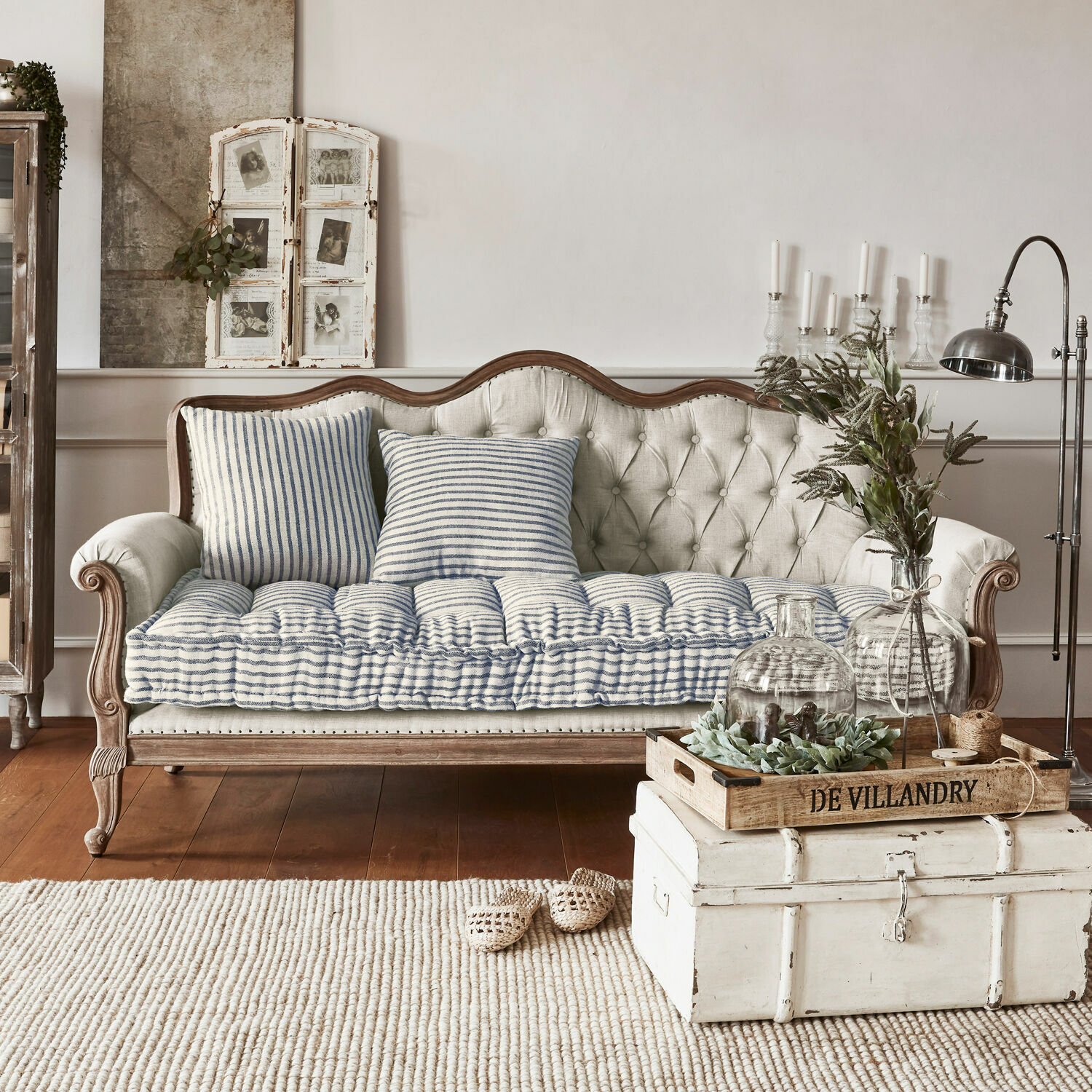Beige gepolstertes Sofa mit Holzrahmen und blau-weiß gestreiften Kissen im Vintage-Stil