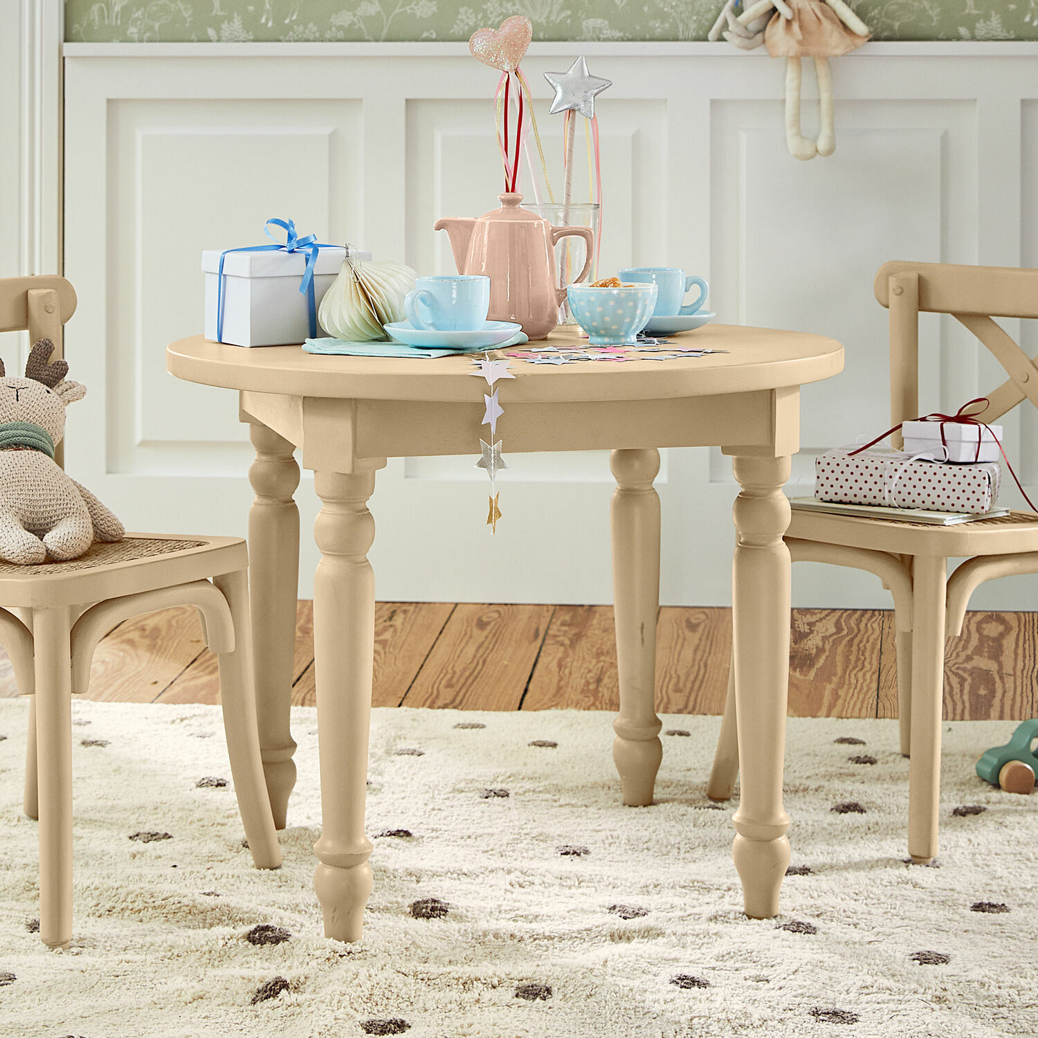 Kindertisch Sourila Beiger runder Kindertisch aus Holz mit Dekorationen und Spielzeug auf gepunktetem Teppich
