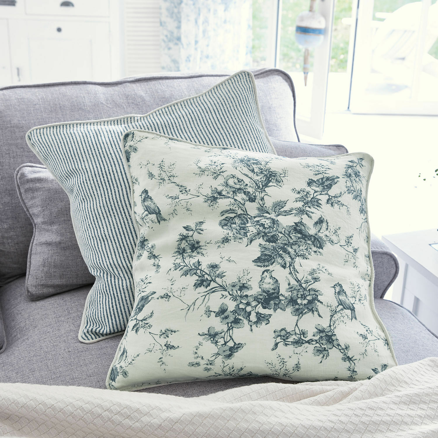 Kissen 2er Set Emilie Wendekissen aus Baumwolle mit blauen Blumen- und Streifenmustern auf grauem Sofa