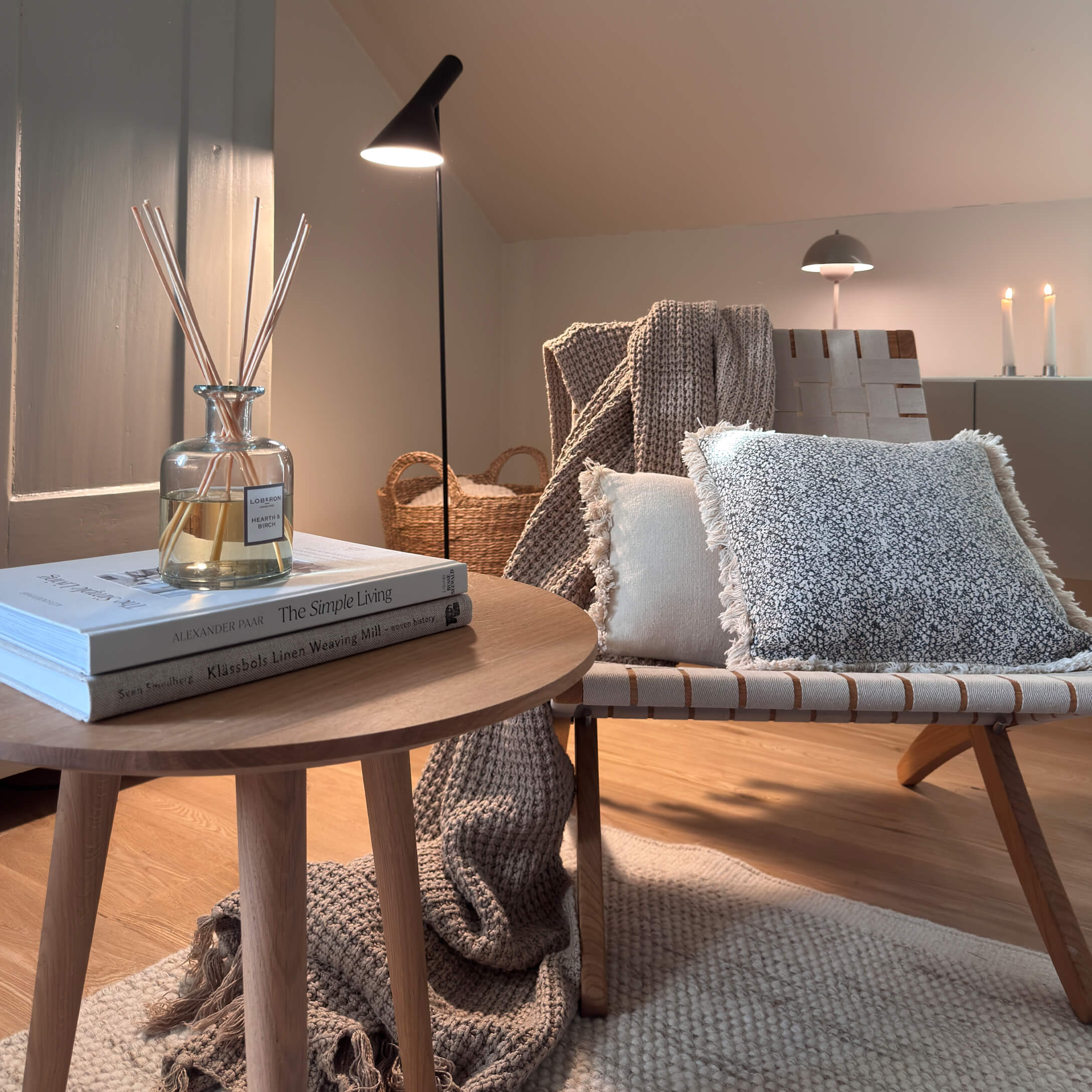 Gemütliche Ecke mit Holztisch, Stehlampe und weichen Kissen in natürlichen Farben für Wohnkomfort