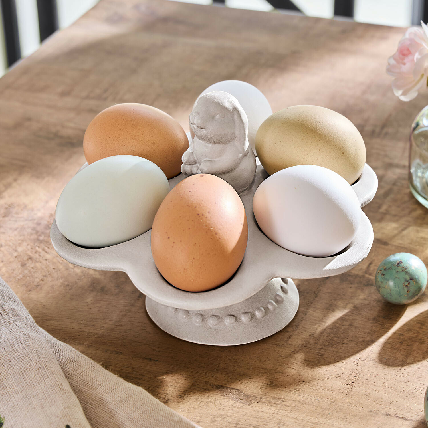 Beiger Keramik-Eierhalter mit Hasenfigur auf rustikalem Holztisch für Ostern