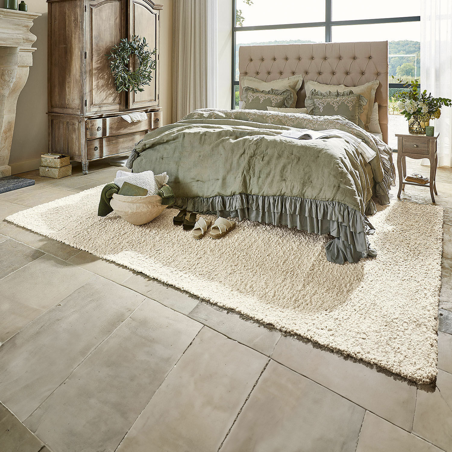 Teppich Wodaha Gemütliches Schlafzimmer mit beige gepolstertem Bett und grüner Bettwäsche auf cremefarbenem Teppich auf Steinboden