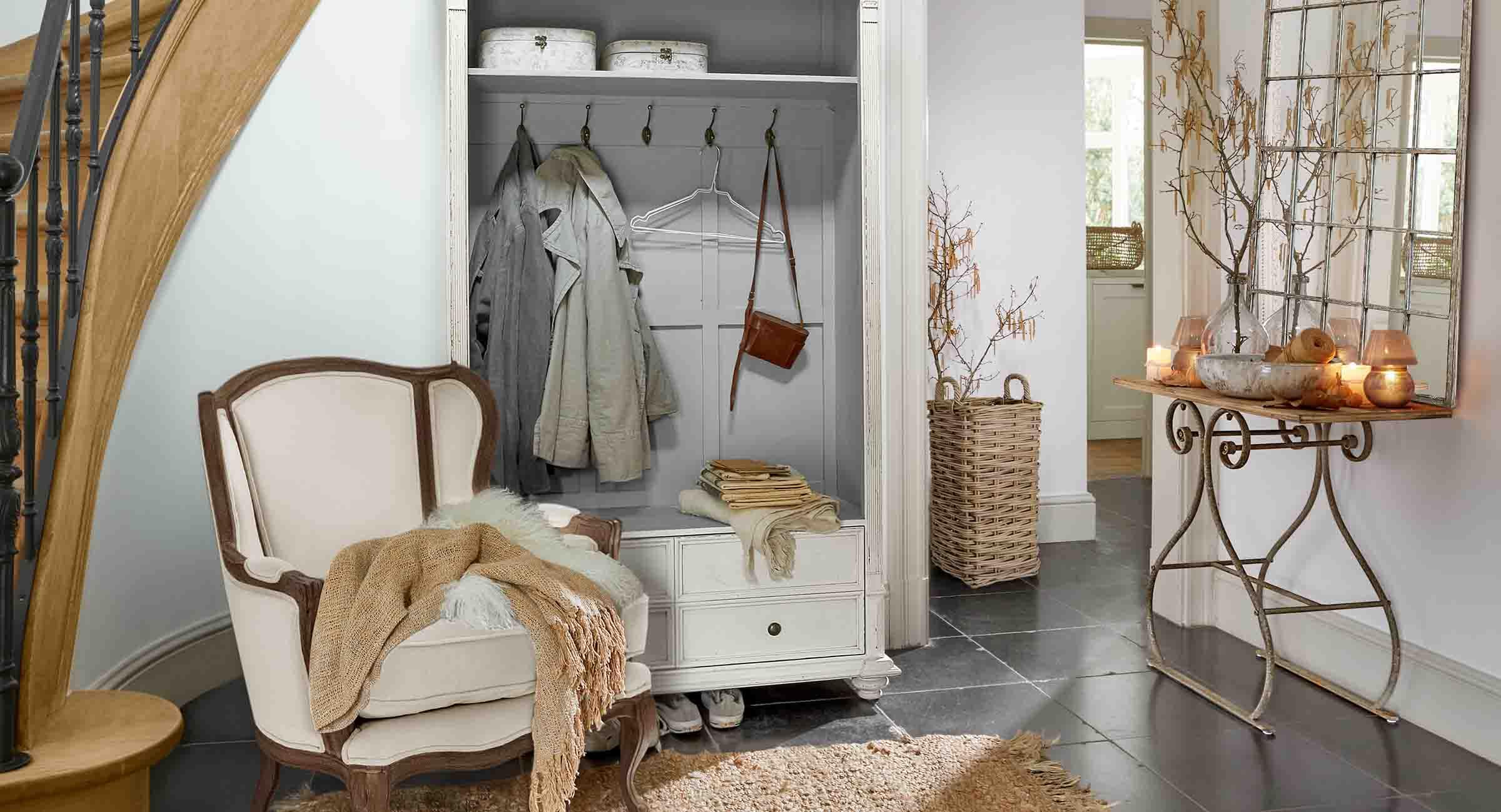 Gemütliche Ecke mit weißem Sessel, Garderobenschrank und Spiegel mit Metallkonsole im Vintage-Stil