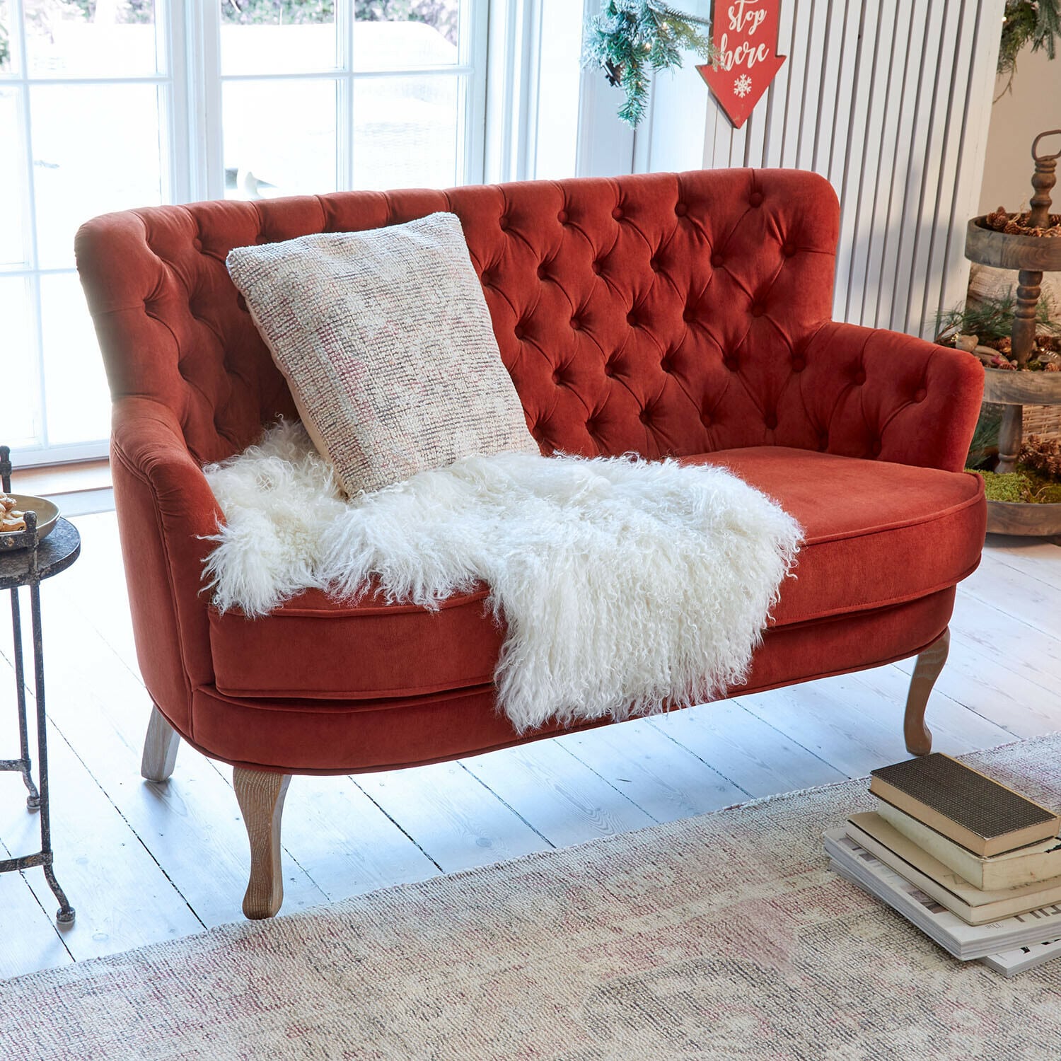 Sofa Calgary Rotes Samtsofa mit gesteppter Rückenlehne und Holzbeinen in hellem, dekoriertem Raum