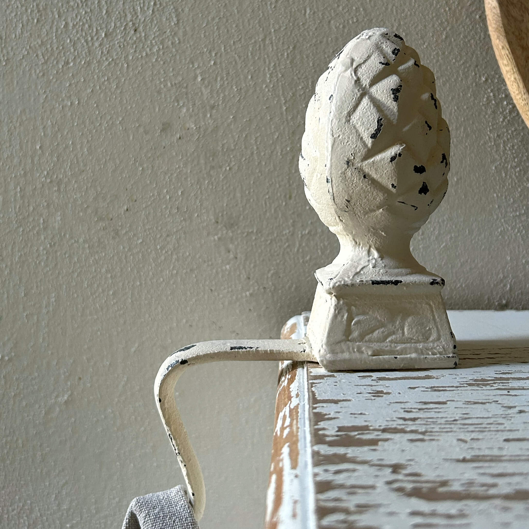 Weißer Metallgriff mit Zapfenornament auf einem antik wirkenden Holzmöbel
